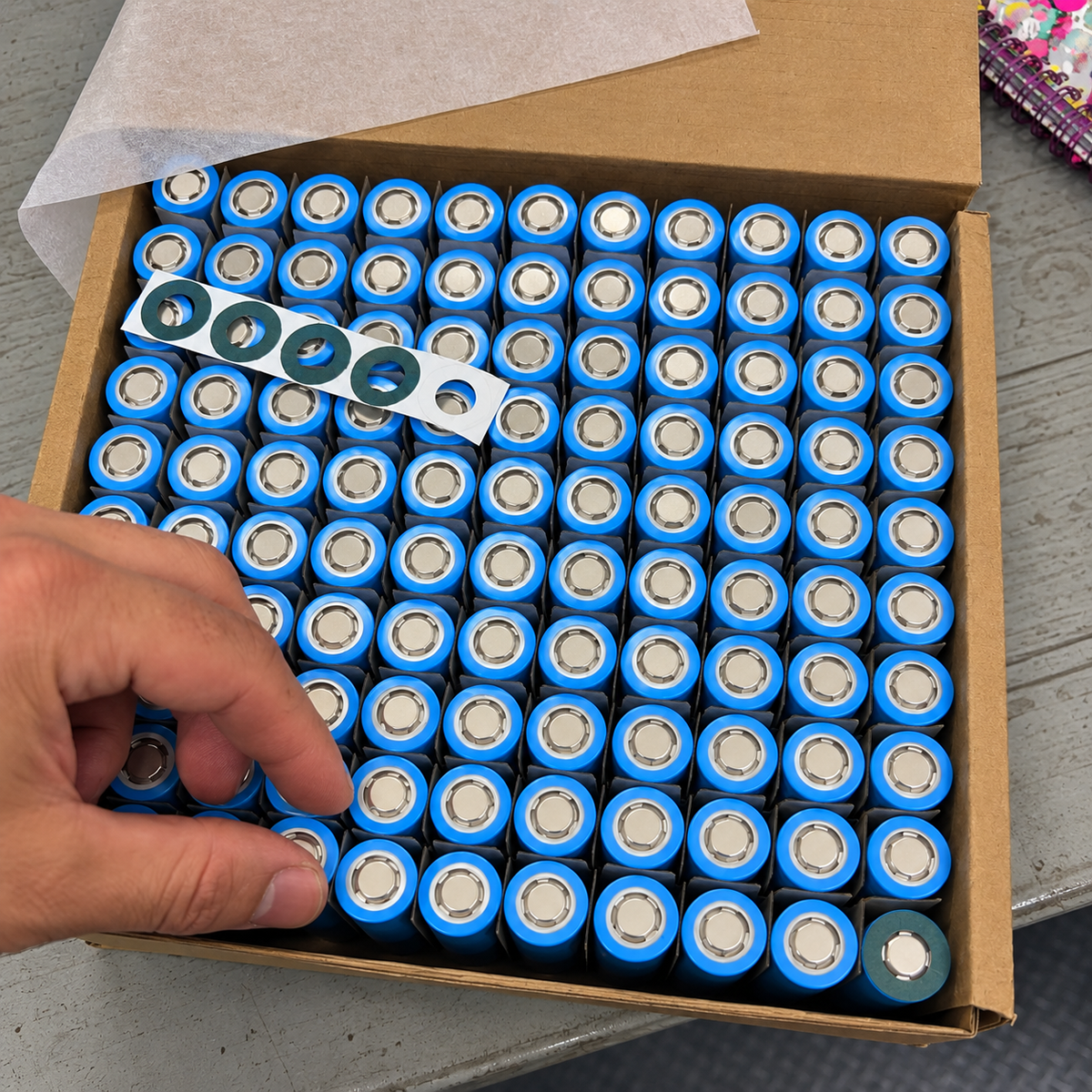 Caja de celdas de litio azules y anillos aislantes en el taller